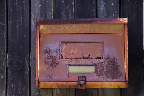 茶色とオレンジに錆びた古い壁付きの郵便受け
