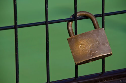 黒い鉄柵に掛けられた古い真鍮の南京錠