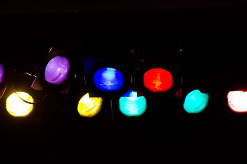 暗闇に横一列で光るカラフルな丸い舞台スポットライト