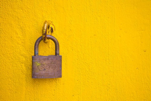 黄色い壁にSOLの文字が彫られた南京錠と鎖