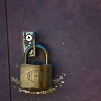 ALPHAの刻印がある金色の南京錠と紫の傷ついた扉の写真