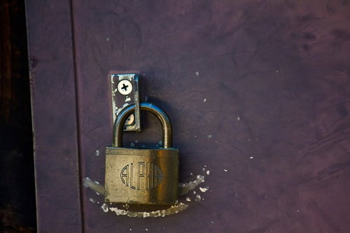 ALPHAの刻印がある金色の南京錠と紫の傷ついた扉