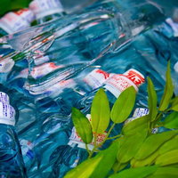 青緑色の水に浮かぶ氷で冷やされたラムネの瓶の写真