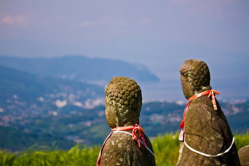 山並みと夕暮れの空を背景に並ぶお地蔵の石仏