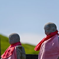 赤いスカーフとピンクの服を着せたお地蔵さん2体の写真