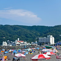 パラソルやテントが並ぶ真夏の賑わうビーチの写真