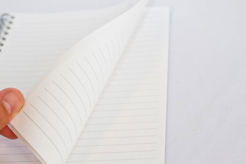 手でページをめくるリングノートの白いページ
