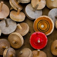 赤と橙のコマを中心に散らばる木製の独楽の写真