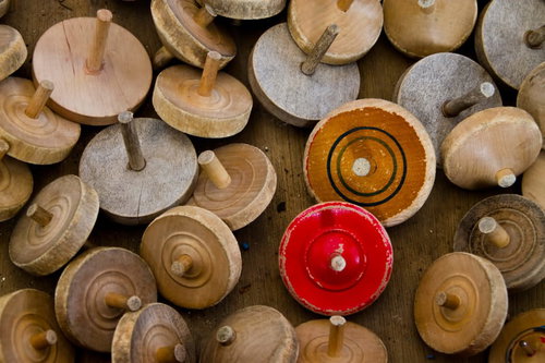 赤と橙のコマを中心に散らばる木製の独楽