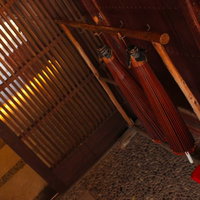 赤い房飾りが吊る木造建築内の昔ながらの傘立ての写真