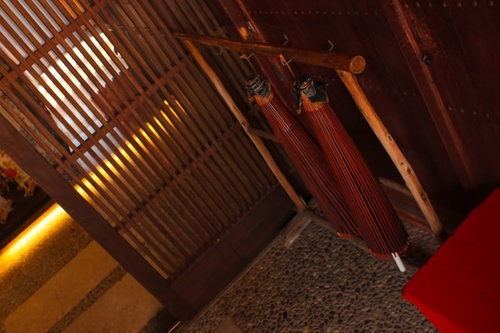 赤い房飾りが吊る木造建築内の昔ながらの傘立て