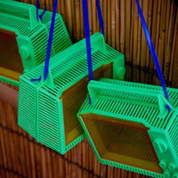 竹の柵の前に吊るされた緑色の虫取りカゴの写真