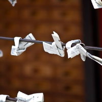 金属ワイヤーに結びつけられた神社のおみくじの写真