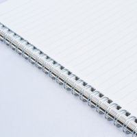 斜めに置かれた白紙のリングノートと銀色のリングの写真