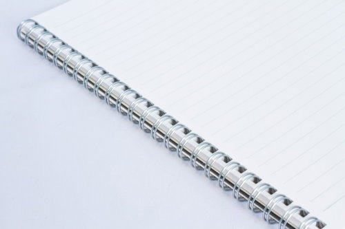 斜めに置かれた白紙のリングノートと銀色のリング