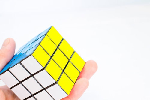青・黄・白の面が見える手に持ったルービックキューブ