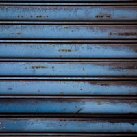 錆が浮き出た青色の金属製シャッターの写真