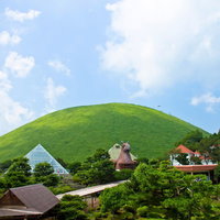 丸い緑の大室山と手前のシャボテン公園の建物群の写真