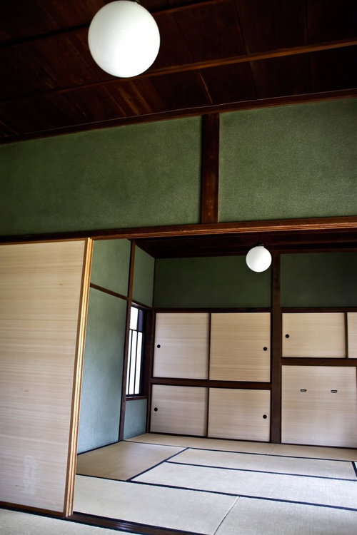 丸い照明と緑の壁が見える畳と襖の和室