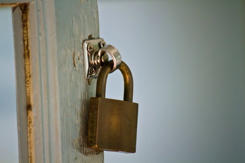 白と青緑の塗装が剥がれた古い扉の金色の南京錠