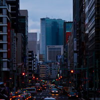 テールランプが光る夕方の日本橋のオフィス街と車の写真