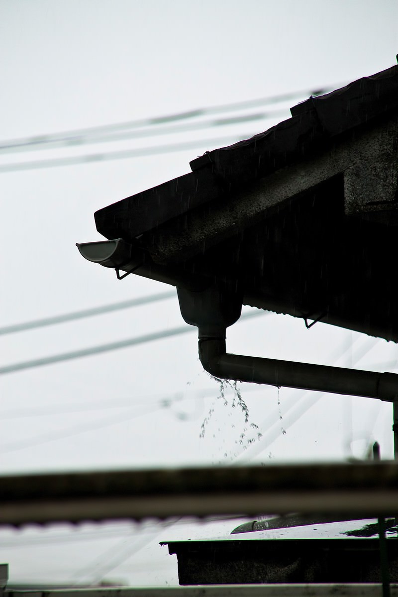 曇り空の下で雨どいからしたたる雨水