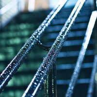 雨に濡れた屋外階段の金属手すりの写真