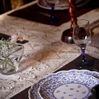 青い花柄の皿とワイングラスのテーブルセッティングの写真