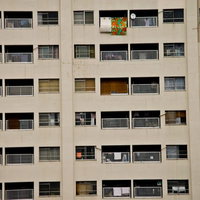 窓やバルコニーが規則的に並ぶベージュの団地の写真