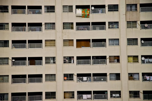 窓やバルコニーが規則的に並ぶベージュの団地
