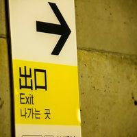 駅の壁に設置された出口への黄色い案内板の写真