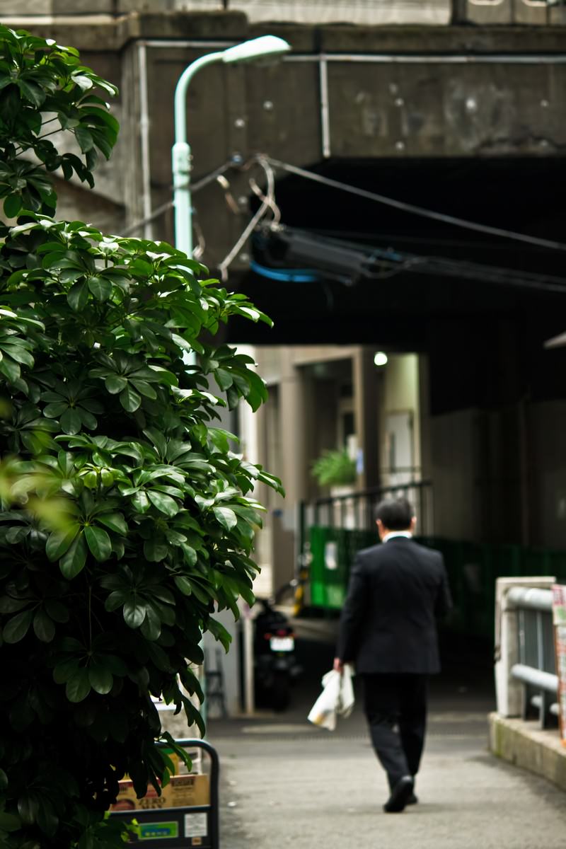 路地を歩く昼下がりのサラリーマンの後ろ姿