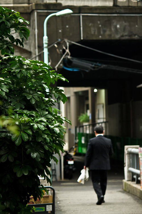 路地を歩く昼下がりのサラリーマンの後ろ姿