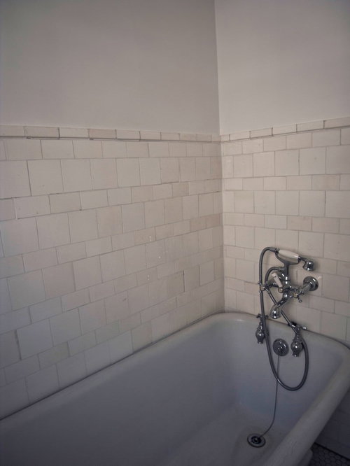 無機質なバスタブと白いタイルの浴室