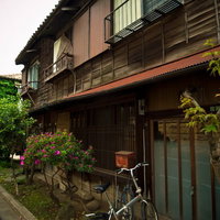 曇り空の下に建つ古い木造二階建てのアパートの写真