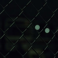 夜の金網越しに見える光の写真