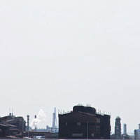 曇り空の下に煙突が並ぶ工業地帯の工場の写真