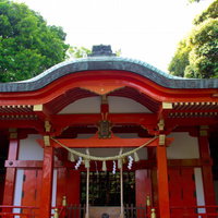 しめ縄と赤い柱が目を引く熊野神社の社殿の写真