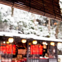 雪が積もる庭園のお茶処と竹の簾の写真