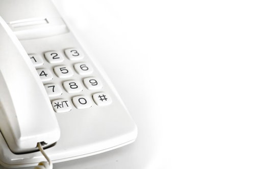 白いボタンが並ぶオフィスの内線電話