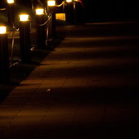 夜道を照らす暖色の照明灯の写真