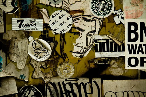 壁に重なって貼られた街角のステッカーやポスター