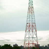 送電線が張られた河川敷の鉄塔の写真