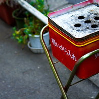 屋外のスタンドに付いた赤い金属の吸殻入れの写真