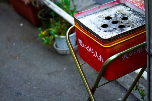 屋外のスタンドに付いた赤い金属の吸殻入れ