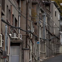 電線が横切る古い建物が並ぶ路地の写真