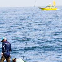 岩場で海釣りをする2人の釣り人の写真