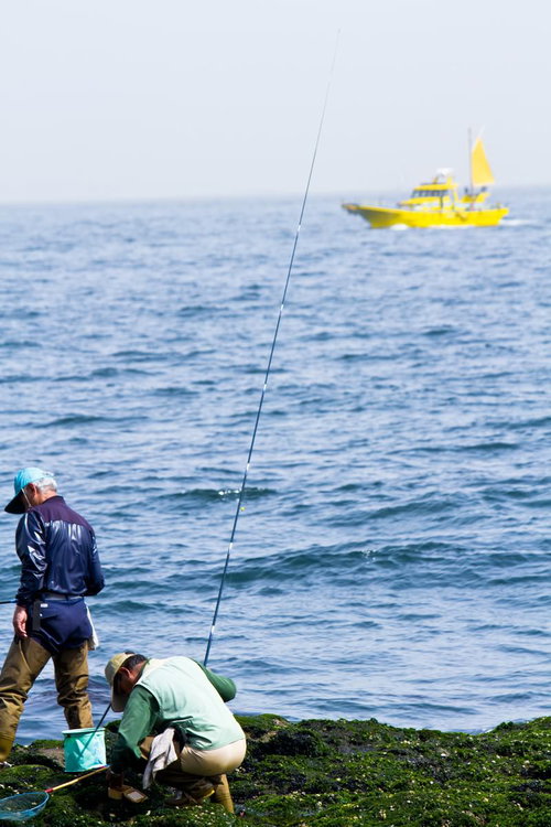 岩場で海釣りをする2人の釣り人