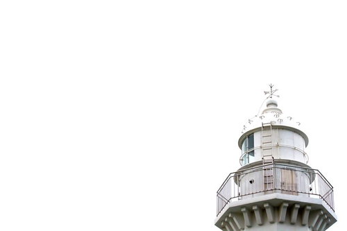 曇り空の下にそびえる白い灯台