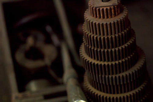 暗い室内で重なり合う金属製のギアと歯車